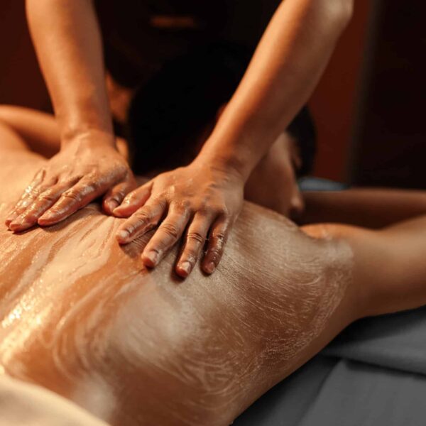 Masseuse hand applying salt scrub on back customer at cosmetology spa centre. Relaxation man customer get service skincare scrubbing massage with masseuse in spa salon. Selective focus.